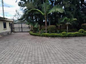Florances Rest House في نيروبي: ممر من الطوب مع سور وأشجار النخيل