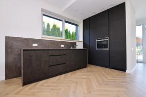 uma cozinha com armários pretos e piso em madeira em MG - Namai em Kaunas