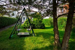 une balançoire dans une cour à côté d'un arbre dans l'établissement Apartament Miriada 16, à Rowy