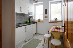 a kitchen with white cabinets and a small table with stools at Apartament Miriada 16 in Rowy