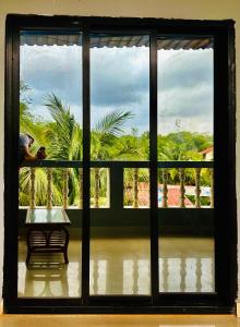 una ventana con vistas al jardín desde una casa en Hotel Baga Bay 200 Meters From Baga Beach en Baga