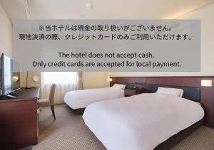 une chambre avec 2 lits et un panneau indiquant que l'hôtel n'accepte pas dans l'établissement 高松パークホテル, à Takamatsu
