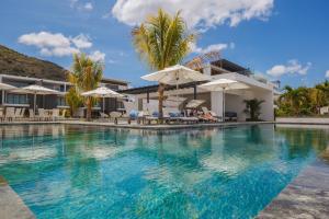 a swimming pool with umbrellas and a house at Latitude By Horizon Holidays in Rivière Noire