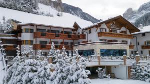 ein großes Gebäude mit schneebedeckten Bäumen davor in der Unterkunft Hotel Muliac in Wolkenstein in Gröden