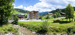 a large building in a village with a grass field at Hotel Unser Unterberg in Maria Alm am Steinernen Meer