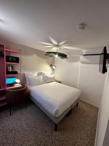 una camera con letto e ventilatore a soffitto di Trendy Canettes Hotel a Parigi