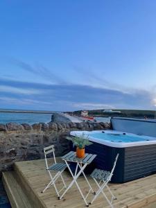 une terrasse avec une table et deux chaises ainsi qu'une piscine dans l'établissement Lighthouse Cottage With Hottub, à Aberdeen