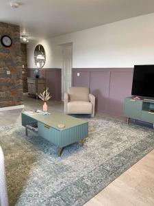 a living room with a couch and a table and a chair at Lighthouse Cottage With Hottub in Aberdeen
