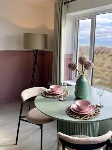 a table with two chairs and a vase with flowers on it at Lighthouse Cottage With Hottub in Aberdeen