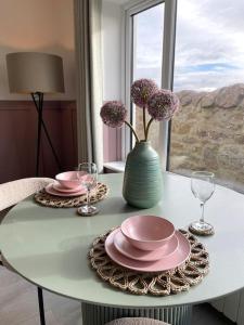 a table with two plates and a vase with flowers on it at Lighthouse Cottage With Hottub in Aberdeen