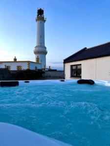 ein Leuchtturm mit einem Leuchtturm im Hintergrund in der Unterkunft Lighthouse Cottage With Hottub in Aberdeen