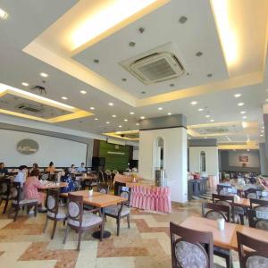 a dining room with tables and chairs and people eating at Mayflower Grande Hotel Phitsanulok in Phitsanulok