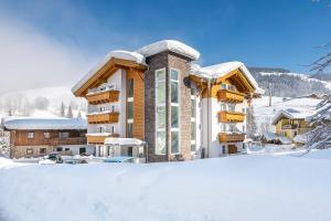 a building with snow on the ground in front of it at Appartements Ferienwohnungen Unser Unterberg in Maria Alm am Steinernen Meer