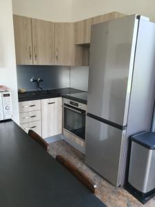 a kitchen with a stainless steel refrigerator and wooden cabinets at LA BÂTISSE l'arbre beige in Le Petit-Abergement
