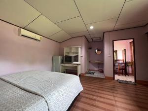 a bedroom with a white bed and a kitchen at Phet Ban Suan Hotel in Ko Chang
