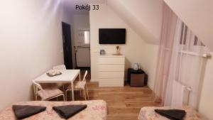 a room with two beds and a table and a television at Pod Dębem in Krynica Morska