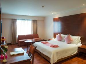 um quarto de hotel com uma cama grande e um sofá em The Palazzo Hotel em Banguecoque