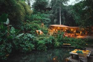 a garden with a pond and a gazebo at Bambu Indah in Ubud