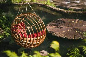 a basket filled with red apples hanging from a pond at Bambu Indah in Ubud