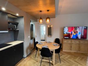 Superbe F3 meublé , hyper centre, fibre, idéal Pro في مونلوسون: غرفة طعام مع طاولة وتلفزيون على الحائط