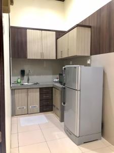 uma cozinha com frigorífico e armários de madeira em Jasmine Villa em Pantai Cenang