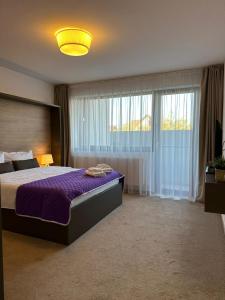 um quarto com uma cama grande e um edredão roxo em Luxury Glam Apartments & Studios near Coresi Mall em Braşov