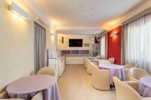 a waiting room with tables and chairs and a kitchen at Hotel Belvir in Villasimius