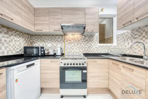 a kitchen with wooden cabinets and a stove top oven at Vivid 2BR at Canal Residences West Dubai Sports City by Deluxe Holiday Homes in Dubai