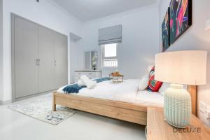 a bedroom with a bed and a lamp at Vivid 2BR at Canal Residences West Dubai Sports City by Deluxe Holiday Homes in Dubai