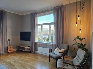 een woonkamer met een stoel, een televisie en een gitaar bij Lovely city center apartment with amazing views and free parking! in Tromsø