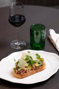 una rebanada de pizza en un plato con una copa de vino en Brussels Marriott Hotel Grand Place, en Bruselas