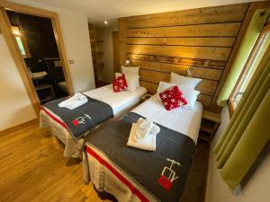two twin beds in a room with wooden walls at MORZINE GUEST CHALET HYPERCENTER Jacuzzi et Sauna in Morzine