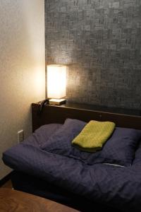 a bed with a green pillow and a lamp at LodgingToyko Minowa formerly Hostel HIDEAWAY in Tokyo