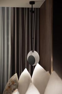 a room with a bed with white pillows and a light at Herloom Hotel & Residence BSD Tangerang in Tangerang