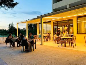 un groupe de personnes assises à des tables sur un patio dans l'établissement Il Grifo Hotel e Bisteccheria Toscana, à Montepulciano