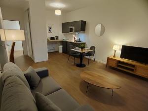 a living room with a couch and a table and a kitchen at Zenao Appart'hôtels Montivilliers in Montivilliers