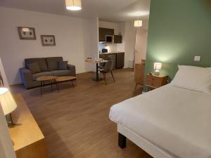 1 dormitorio con 1 cama y sala de estar con sofá en Zenao Appart'hôtels Montivilliers, en Montivilliers