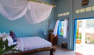 sypialnia z łóżkiem z niebieskimi ścianami i oknem w obiekcie La Mer - Vĩnh Hy bay - beachfront villa CHÀI w mieście Vinh Hy Bay