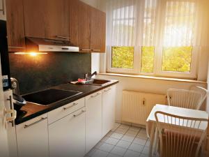 cocina con armarios blancos, fregadero y mesa en Appart-Haus Business Apartments, en Lingen