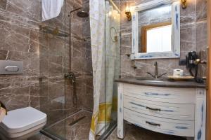 a bathroom with a shower and a sink and a toilet at Orchis Hotel in Ayvalık