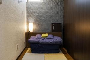 a small room with a bed with a yellow pillow at LodgingToyko Minowa formerly Hostel HIDEAWAY in Tokyo