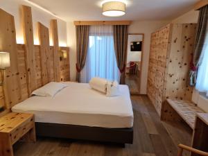 1 dormitorio con 1 cama y paredes de madera en Hotel Muliac en Selva di Val Gardena