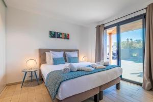 a bedroom with a bed and a large window at Résidence Pierre & Vacances Premium Vesna Rossa in Porto-Vecchio
