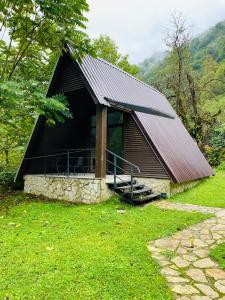 a small cabin with a black roof on a grass field at Mtirala National Park hotel ORBEZA in K'obulet'i