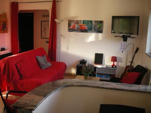 a living room with a red couch and a tv at Villa NERO BIANCO, Havre de paix, oliviers, piscine privée in Agrigento