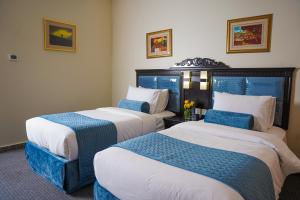 two beds in a hotel room with blue and white at AG Hotel in Abu Dhabi