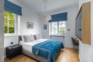 a bedroom with a bed and two windows at Grand Tulipan in Gdynia
