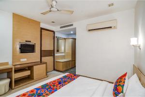 a bedroom with a bed and a tv and a bathroom at FabExpress Vasundhara Suits in Ghaziabad
