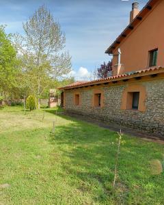 a stone building with a grass yard in front of it at Granja de Cantarinas in Ciudad-Rodrigo