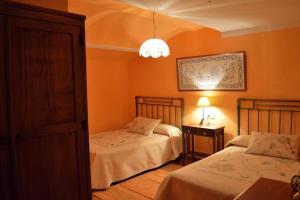 two beds in a room with orange walls at Granja de Cantarinas in Ciudad-Rodrigo